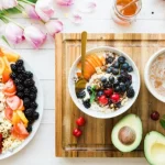 Frühstück mit Müsli, Kaffee, frischer Avocado und bunt angerichtetem Obst
